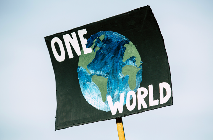 Schild mit der Aufschrift 'One World' als Symbol für globale Klimaschutz-Maßnahmen