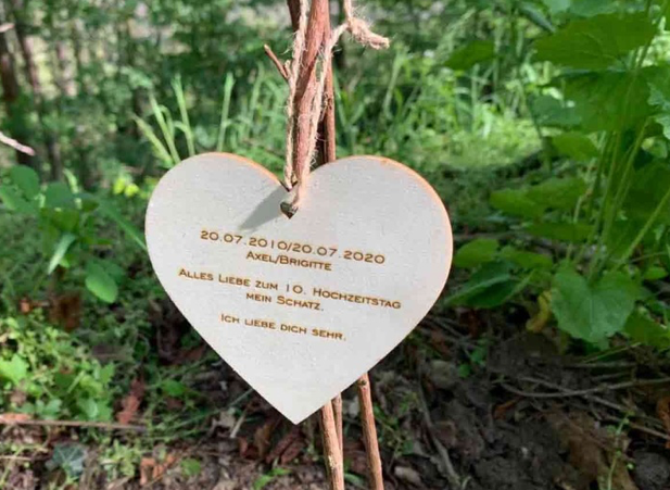 Ein Holzherz mit eingravierten Namen der Baumpartner und einer Widmung.